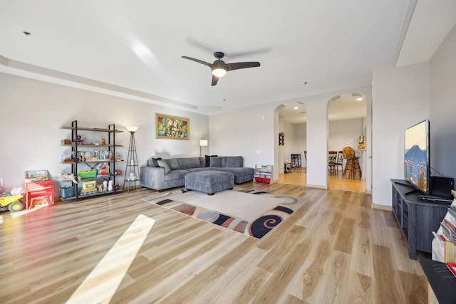 living room featuring ceiling fan, arched walkways, and wood finished floors