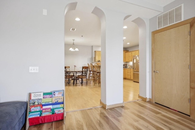 interior space with arched walkways, visible vents, light wood finished floors, and recessed lighting