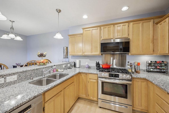 kitchen featuring hanging light fixtures, appliances with stainless steel finishes, light brown cabinets, a sink, and light stone countertops