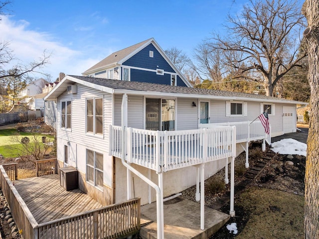 rear view of property featuring a shingled roof and a wooden deck