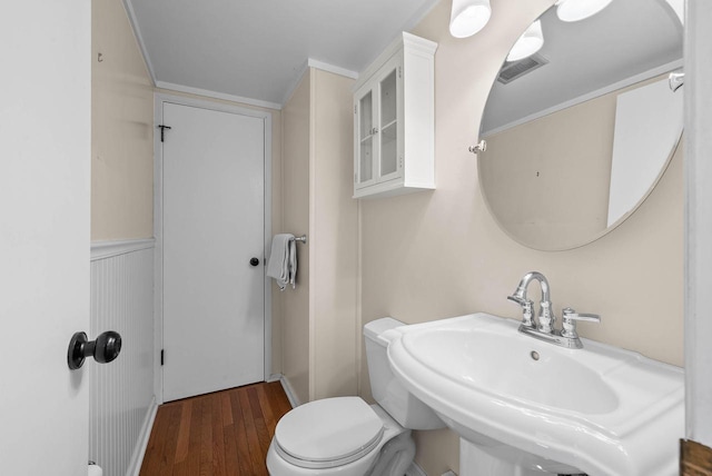 bathroom featuring toilet, wood finished floors, a sink, and visible vents