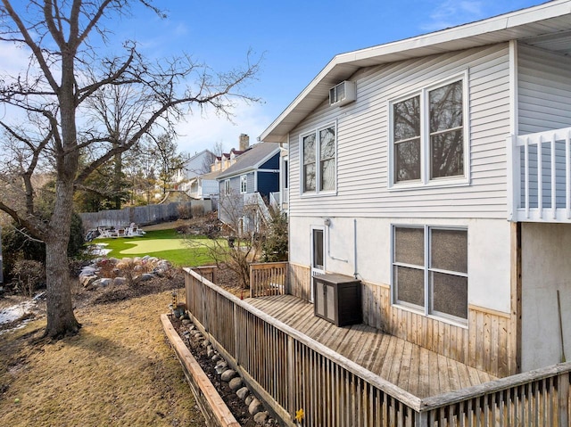 view of home's exterior with a deck, a lawn, fence, and stucco siding