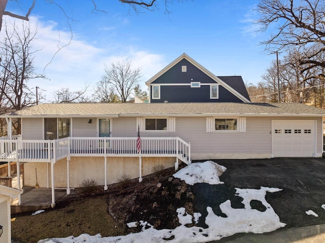 view of front of home with a garage, aphalt driveway, and roof with shingles