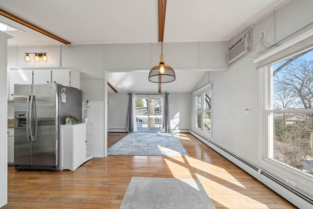 kitchen with light wood-style floors, a baseboard radiator, a wall unit AC, and stainless steel refrigerator with ice dispenser