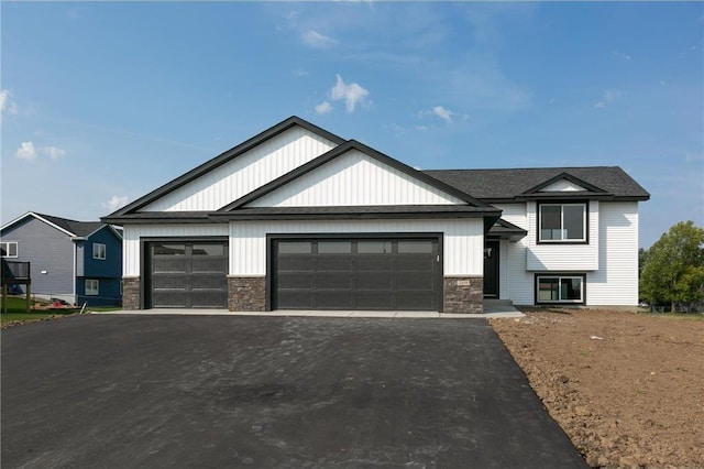 view of front of home featuring stone siding, an attached garage, and driveway