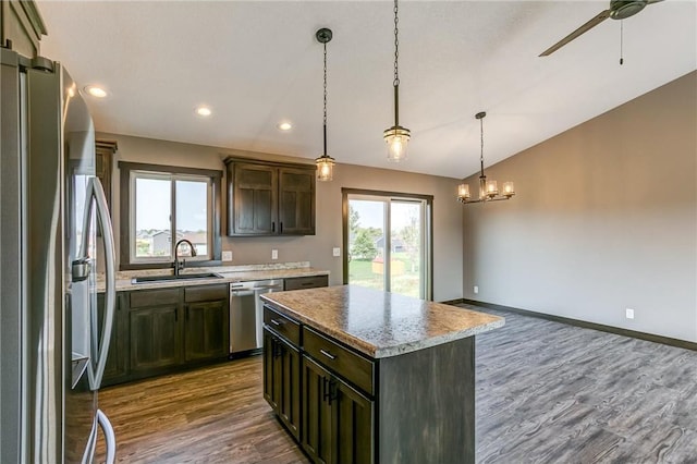 kitchen with a sink, vaulted ceiling, appliances with stainless steel finishes, a wealth of natural light, and a center island