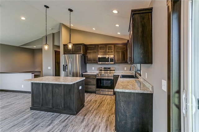 kitchen with stainless steel appliances, a sink, dark brown cabinets, light countertops, and light wood finished floors