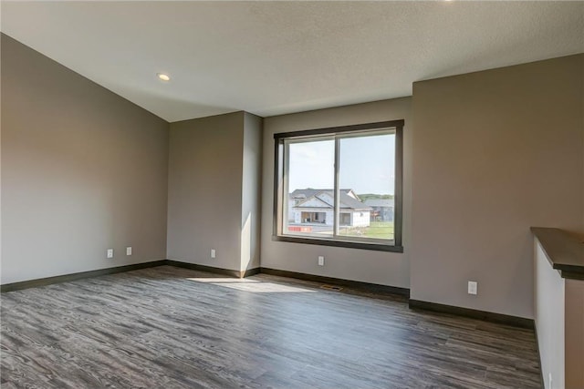 spare room with dark wood-style floors, baseboards, and a textured ceiling