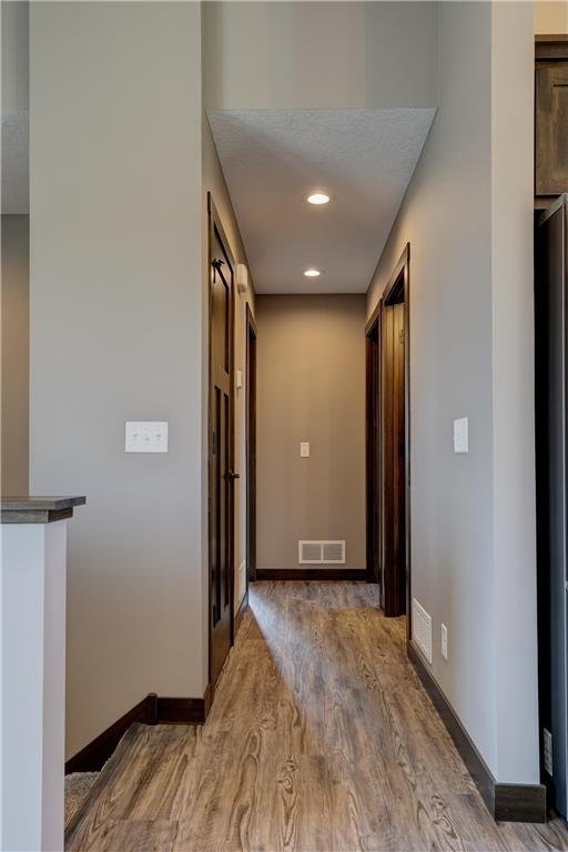 hall featuring recessed lighting, wood finished floors, visible vents, and baseboards