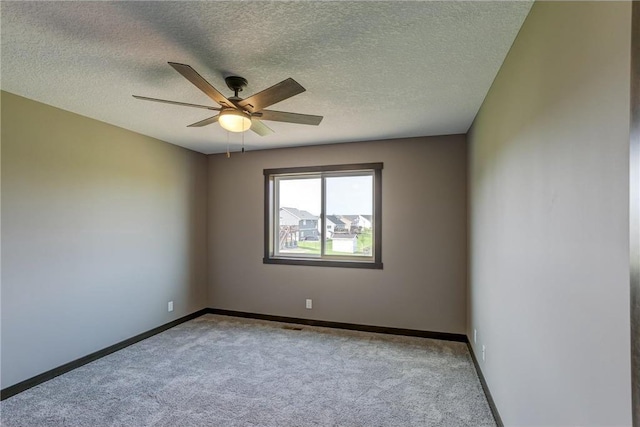 empty room with light carpet, ceiling fan, baseboards, and a textured ceiling