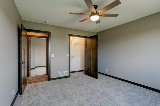 unfurnished bedroom with light carpet, baseboards, visible vents, a ceiling fan, and a closet