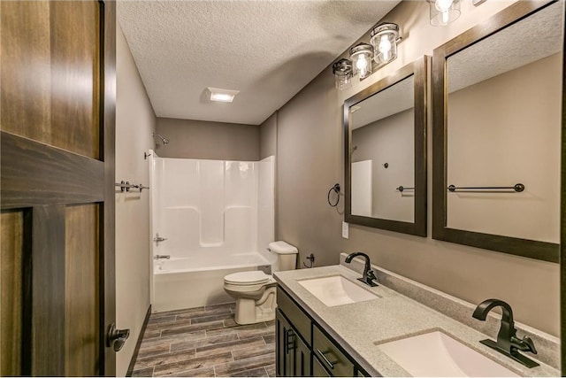 full bathroom featuring wood finish floors, a sink, a textured ceiling, and toilet