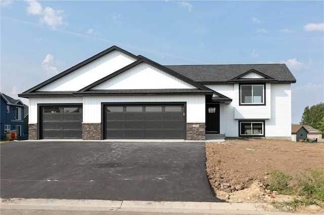 view of front of home with a garage, stone siding, and aphalt driveway