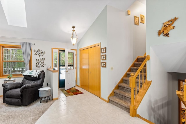 entryway with light colored carpet, vaulted ceiling with skylight, a healthy amount of sunlight, and stairs