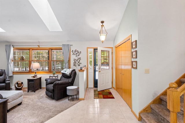 foyer with light carpet, light tile patterned floors, baseboards, lofted ceiling with skylight, and stairway