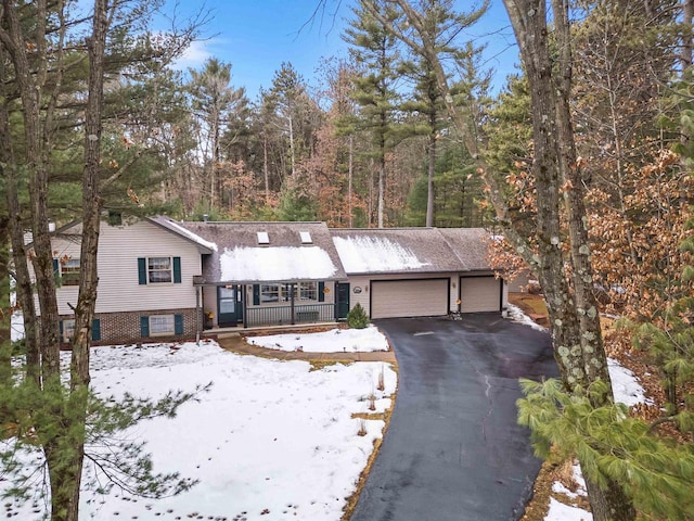 split level home with aphalt driveway, brick siding, and an attached garage