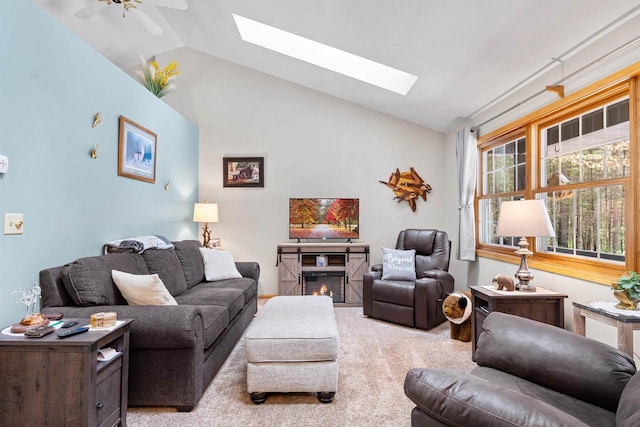 living room with vaulted ceiling with skylight, carpet, and a glass covered fireplace