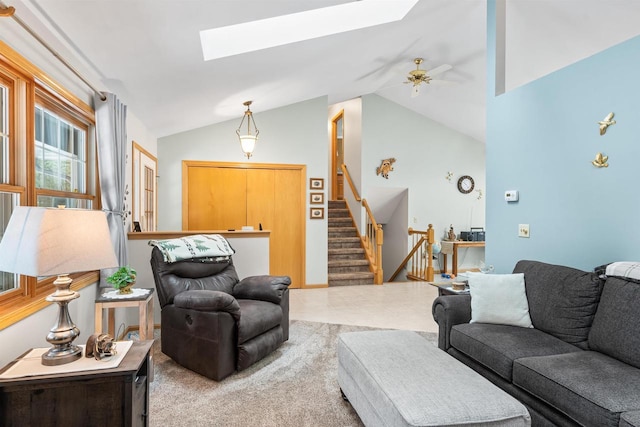 living area featuring stairs, ceiling fan, and lofted ceiling with skylight