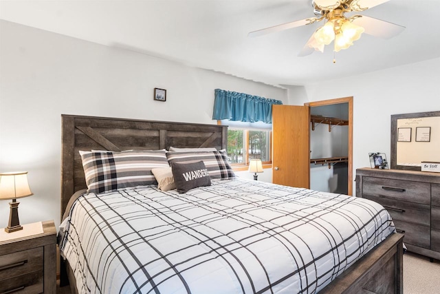 carpeted bedroom featuring a walk in closet, a closet, and ceiling fan