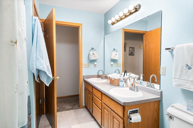 bathroom featuring double vanity, tile patterned flooring, toilet, and a sink