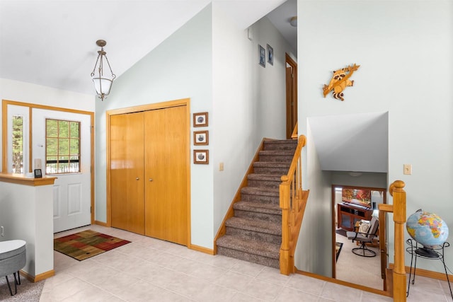 entryway featuring baseboards, stairway, vaulted ceiling, and light tile patterned flooring