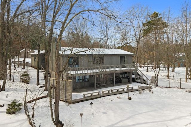 snow covered house featuring a deck and stairs