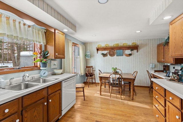 kitchen with light countertops, dishwasher, light wood-style flooring, and a sink