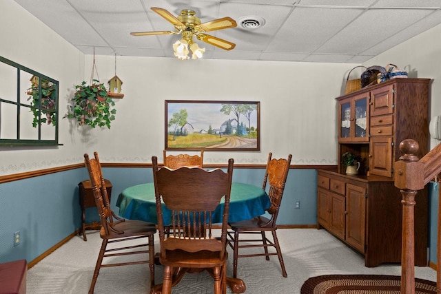 dining area with a drop ceiling, light carpet, visible vents, baseboards, and a ceiling fan