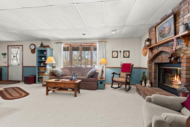 carpeted living area with a drop ceiling and a fireplace