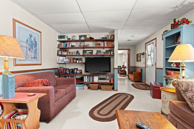 living area featuring a wainscoted wall and a paneled ceiling