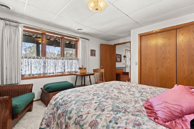 bedroom featuring carpet, a closet, visible vents, and a paneled ceiling