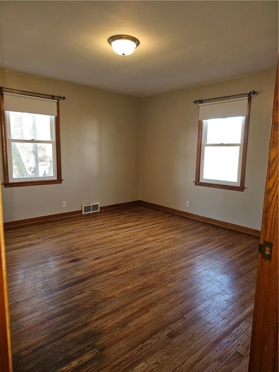 spare room featuring dark wood-style floors, baseboards, and visible vents