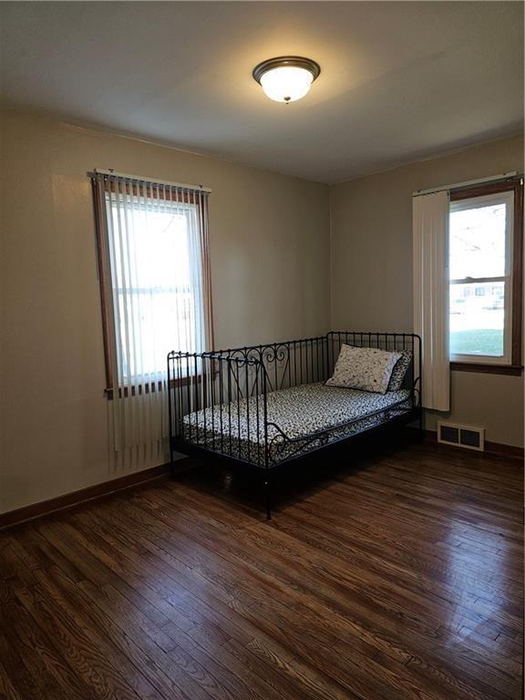 unfurnished bedroom featuring wood finished floors, visible vents, and baseboards