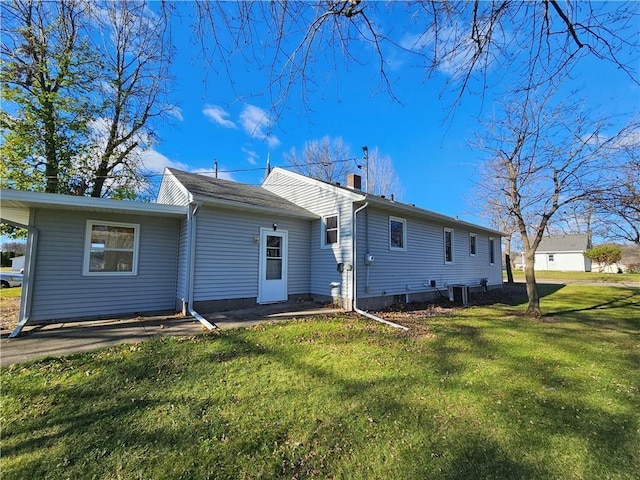 rear view of house with a chimney, central AC, and a lawn