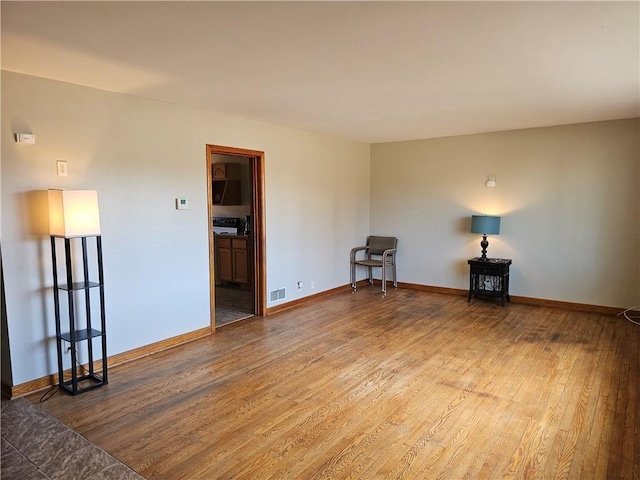 unfurnished room featuring baseboards, visible vents, and wood finished floors