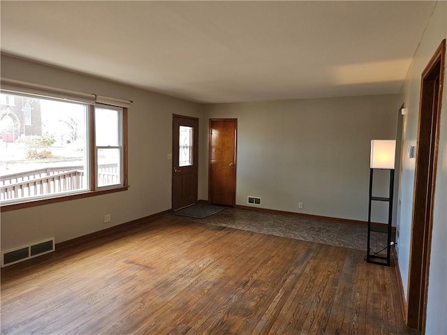 interior space with dark wood-type flooring, visible vents, and baseboards