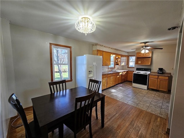 dining space with wood finished floors and ceiling fan with notable chandelier