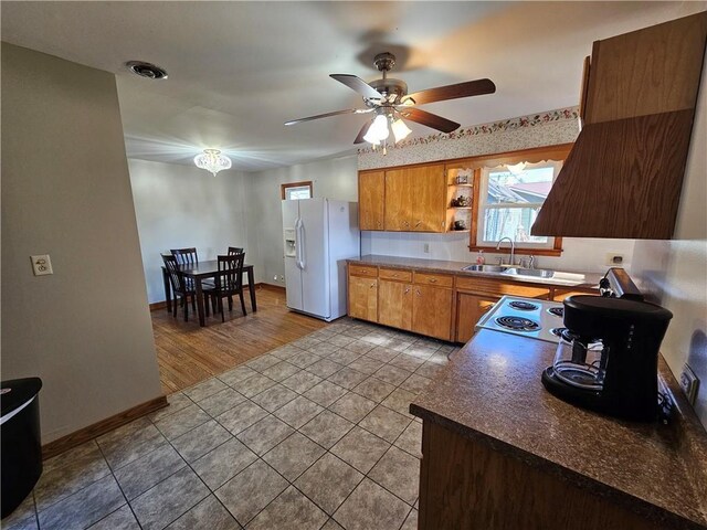 kitchen featuring open shelves, a sink, white fridge with ice dispenser, tile patterned flooring, and baseboards