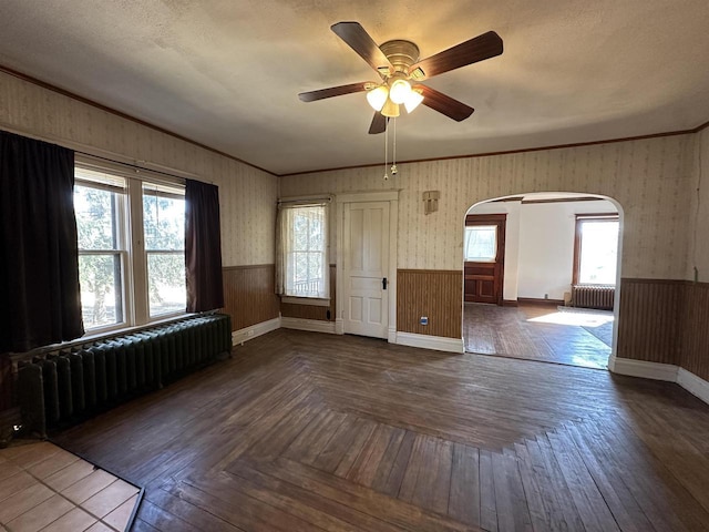 spare room with wallpapered walls, radiator heating unit, and a wainscoted wall