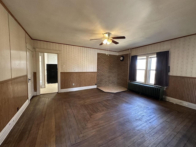 spare room featuring a wainscoted wall, radiator heating unit, ornamental molding, and wallpapered walls