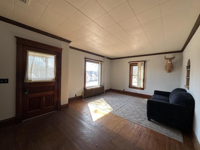 interior space with radiator, baseboards, ornamental molding, and dark wood finished floors