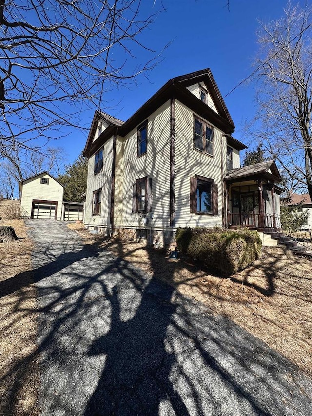 view of home's exterior featuring a garage, an outbuilding, and covered porch