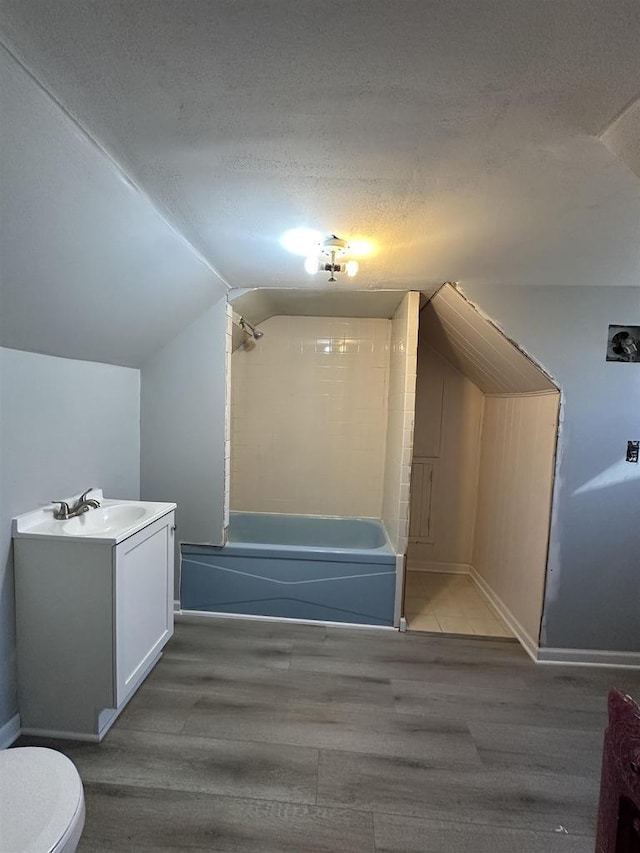 bonus room with vaulted ceiling, a textured ceiling, and wood finished floors