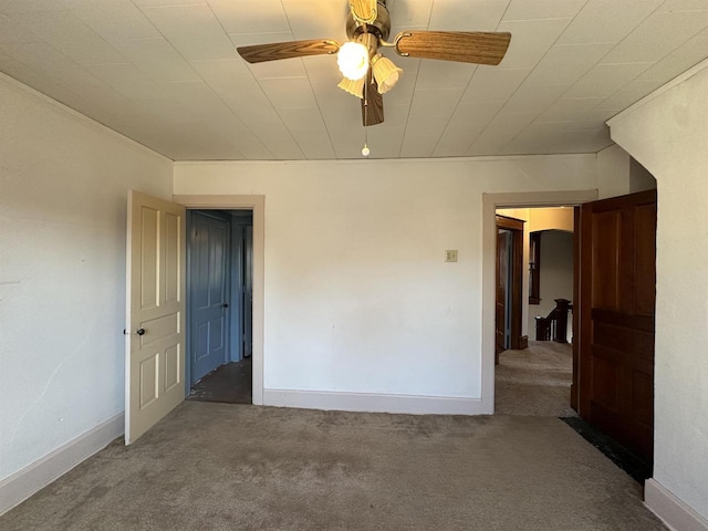 carpeted empty room featuring a ceiling fan and baseboards