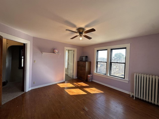 unfurnished bedroom with radiator, a ceiling fan, baseboards, and hardwood / wood-style floors