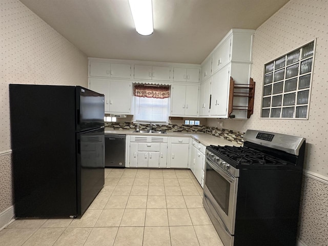 kitchen featuring dishwashing machine, stainless steel gas range oven, a sink, freestanding refrigerator, and wallpapered walls