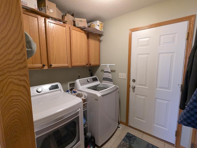 clothes washing area featuring a textured ceiling, separate washer and dryer, light tile patterned flooring, and cabinet space