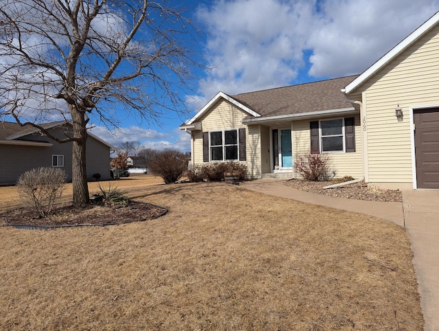 ranch-style home with a garage, roof with shingles, and a front yard