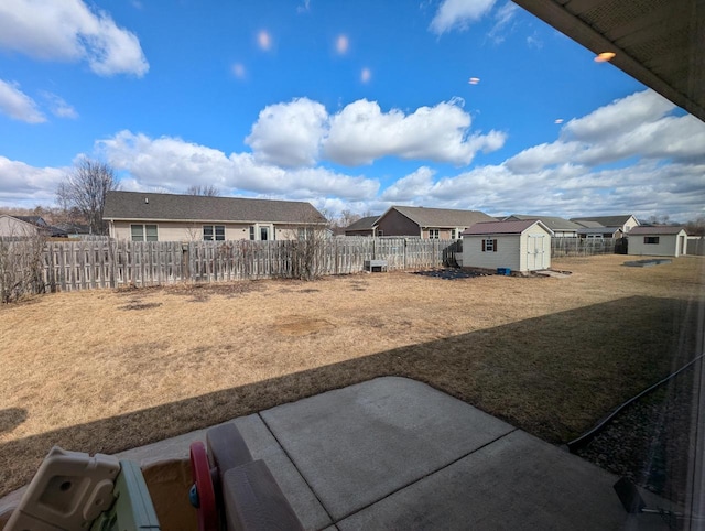 view of yard featuring an outbuilding, a storage shed, a patio area, a residential view, and a fenced backyard