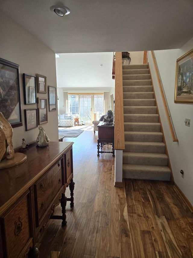 corridor featuring stairs, baseboards, and dark wood-type flooring